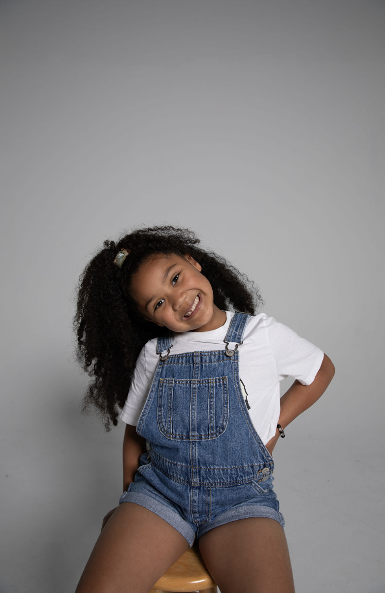 Iman smiling in denim overalls
